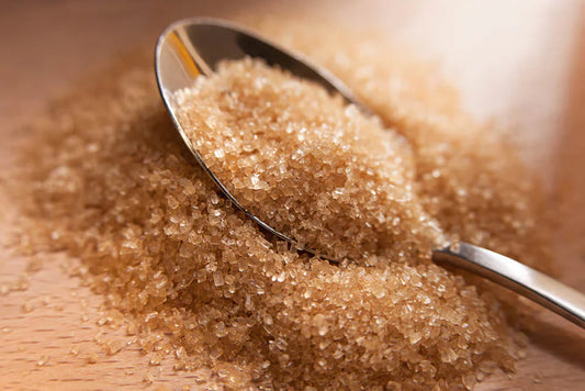 NuEats Organic Sugar crystals with a silver spoon on a rustic wooden background, showcasing the natural, unrefined texture of premium cane sugar for wellness-focused baking.